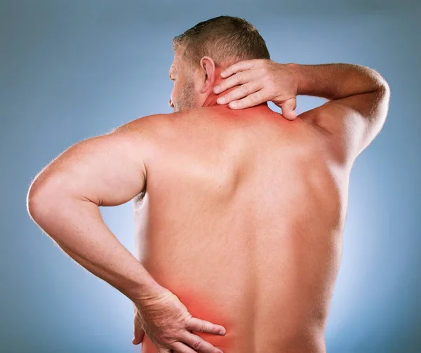 Back, man and pain with inflammation, injury and body ache with blue studio background. Mature male, gentleman or emergency with neck, bruise or broken with red highlight for muscle tension or strain.