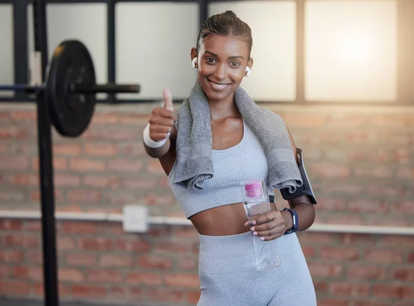 Woman, fitness and portrait smile with thumbs up for good job, workout success or thank you with water bottle at gym. Happy sporty female smiling showing thumb up emoji, yes sign or like for exercise.