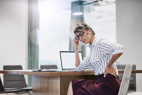 Stress, bad for her back and bad for business. a young businesswoman experiencing back pain while working in an office