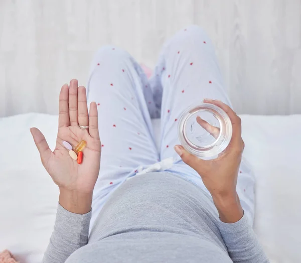 Pills, water and woman hands for pregnancy health, growth and wellness. Pregnant person in home bedroom above glass and Pharma medicine supplement, nutrition and iron or magnesium for development.