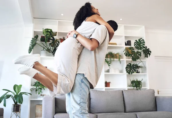 Young couple, hug and jump in new house, real estate and apartment lounge with love. Happy homeowners hugging to celebrate in living room, property investment and dance with care, energy or happiness.