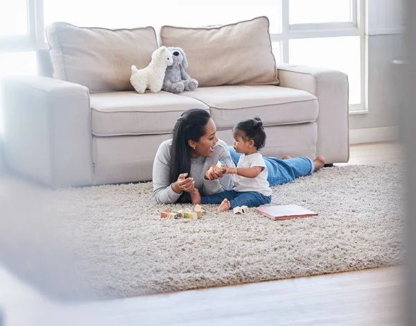 Baby, mom and living room fun of a mother and kid with toys for knowledge development. Smile, happiness and parent care on a lounge rug in a home with mama love and bonding together with a child.