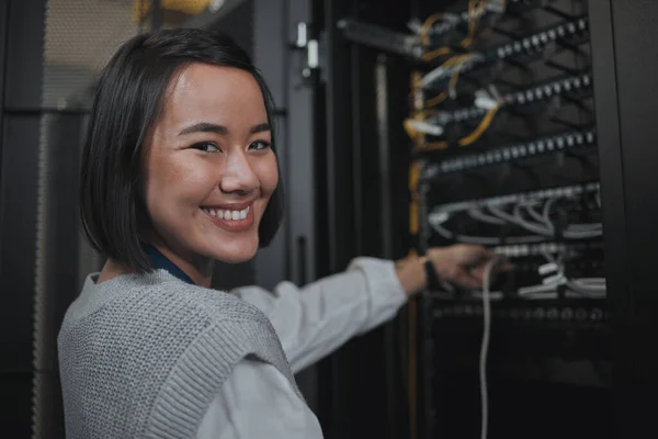 Asian woman, portrait smile and technician by server for networking, maintenance or systems at office. Happy female engineer smiling for cable service, power or administration in data center room.