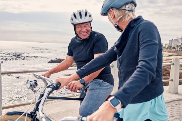 Bike, cycling and beach with a senior couple riding outdoor on the promenade during summer for exercise. Bicycle, fitness or leisure with a mature man and woman taking a ride together on their bikes.