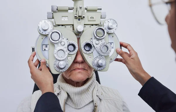 Eyes, vision exam and senior woman with optometrist in clinic for test, eyesight and optical assessment. Optometry, healthcare and optician with elderly patient, phoropter lens and medical machine.