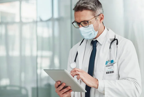 Hospital, research and doctor with tablet and mask for wellness, medical care and patient data. Healthcare, insurance and senior man on digital tech for online consulting, report and telehealth app.