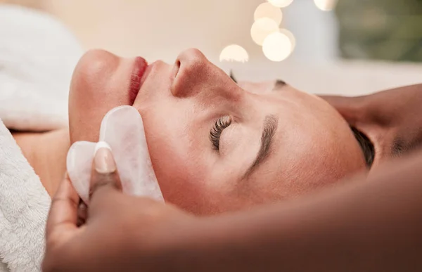 Gua sha, skincare and woman getting a face massage for wellness, health and self care at a spa. Beauty, cosmetic and calm young female doing a luxury facial treatment with rose quartz at a zen salon