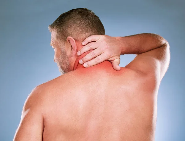 Back, senior man and neck pain with stress, emergency and guy against blue studio background. Mature male, gentleman and injury with muscle strain, tension and burnout with first aid and suffering.