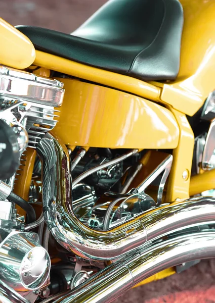 Closeup of a custom design motorbike with chrome leather seat. Details of a yellow luxury motorcycle. An upgrade to a motorcycle with expensive motor components at an auto parts and service store.