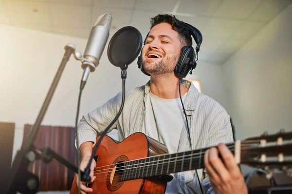 Guitar, microphone and singing in studio for album recording, theatre label or radio musician industry. Man, singer and guitarist headphones for instrument production, theater sound or karaoke media.