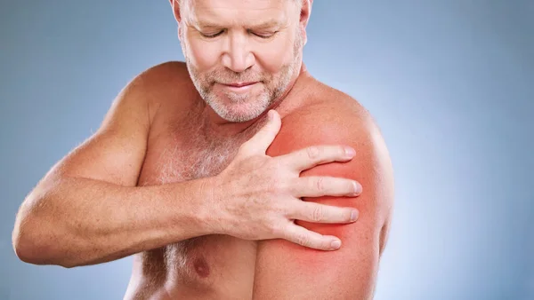 Senior man, arm pain and red glow on muscle or body on a blue background in studio with arthritis. Elderly model person with hand on injury, anatomy health problem or broken bone medical risk.