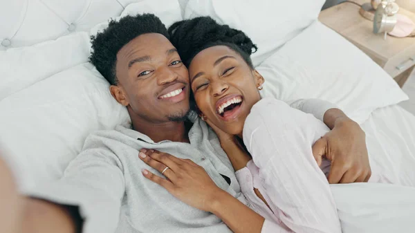 Selfie and happy influencer couple vlogging their honeymoon while lying in bed to love and relax together at home. Portrait of a loving black man and woman having romantic moment in the morning.