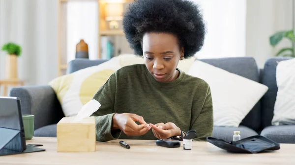Happy African American woman using a glucose monitoring device at home. Smiling black female checking her sugar level with a rapid test result kit, daily routine of diabetic care in a living room.