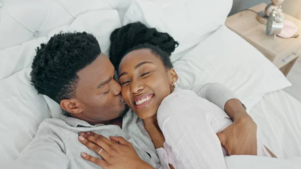 Selfie, kiss and happy influencer couple vlogging their honeymoon while lying in bed to love and relax together at home. Portrait of a loving black man and woman having romantic moment in the morning.