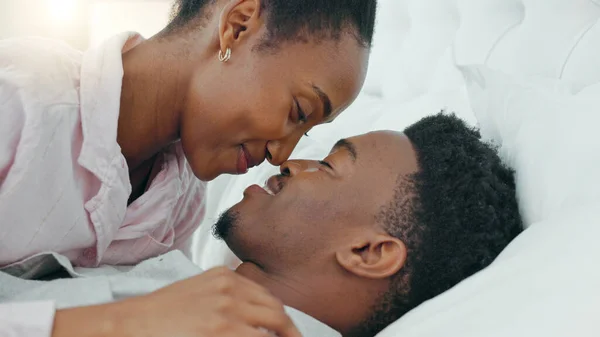 Love, smile and happy intimate couple in bed in the morning while talk and bonding together. Black man and woman relax, conversation and communication trust, support and quality time in home bedroom.