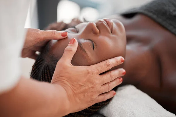 Beauty, relax and black woman getting a facial massage for health, wellness and self care. Skincare, spa and calm African female sleeping while doing a luxury natural face treatment at a salon