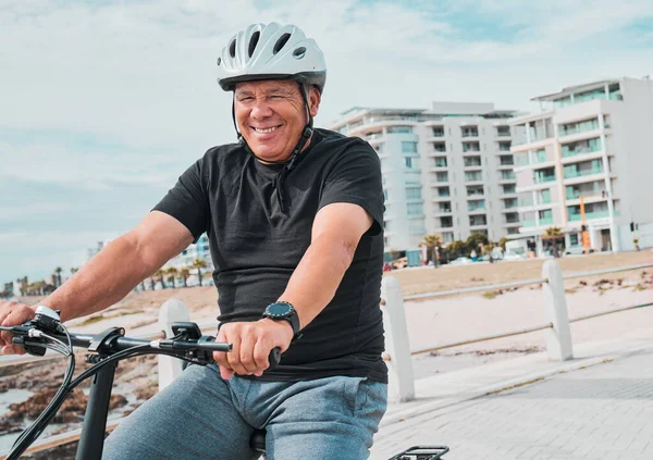 Mature man, helmet or electrical bike by beach for future fitness, clean energy transport or sustainability travel. Happy person, technology or electric bicycle, head safety or eco friendly cycling.