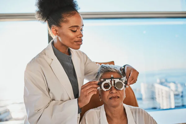 Senior eye exam, black woman doctor and medical eyes test of elderly female at consultation. Vision, healthcare focus and old patient with consulting wellness expert for lens and glasses check.