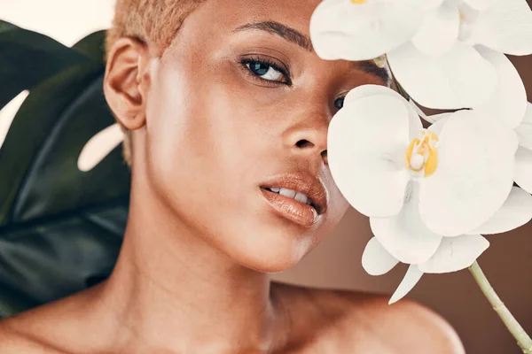stock image Flower, portrait and black woman with cosmetics, dermatology and treatment for wellness and confidence. Face, female and lady with plant, orchid and natural care for luxury, healthy and smooth skin.