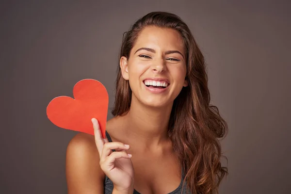 Happy heart, happy life. Studio shot of an attractive young woman holding a blank red heart against a gray background