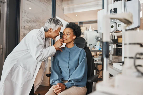 Doctor, vision or black woman in eye exam consultation or assessment for eyesight at optometrist office. Mature or senior optician helping a customer testing or checking iris or retina visual health.