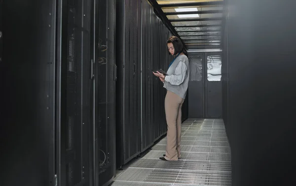 Tablet, server room and data center with a programmer asian woman at work on a computer mainframe. Software, database and information technology with a female coder working alone on a cyber network.