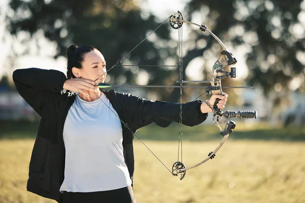 Happy person, bow or arrows aim in sports field, shooting range or gaming nature in hunting, hobby or exercise. Archery, woman or athlete smile with weapon in target training, competition or practice.