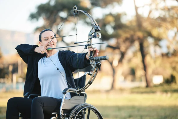 Disabled sports woman, outdoor archery in wheelchair and challenge with active lifestyle in Canada. Person with disability in a park, fitness activity to exercise arms and aim arrow for hobby.