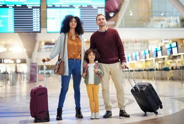 Family, holding hands at airport and travel for holiday, parents and child look at flight schedule for vacation. Interracial, adventure and people at airline, transportation and journey with luggage.