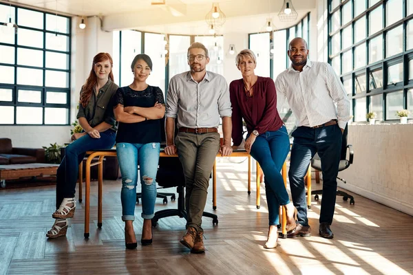 Were a team because we work together. Portrait of a group of confident businesspeople standing together in a modern office