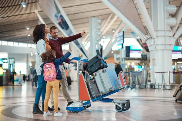 Family at airport, travel and vacation with luggage, mother and father with child, ready for flight and adventure. Terminal, journey and holiday with black woman, man and kid with suitcase on trolley.