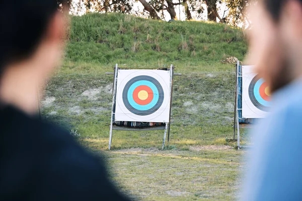 Target, archery coach or bow and arrow learning for archer competition, athlete challenge or girl training practice. Sports teacher, teaching talk or man coaching woman on precision, aim and shooting.