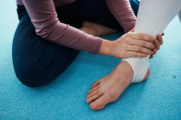 Injury, hurt and foot or ankle pain for athlete getting help from coach, trainer and sport or gymnastics practice. Person, emergency and closeup of people feet swollen muscle due to exercise accident.