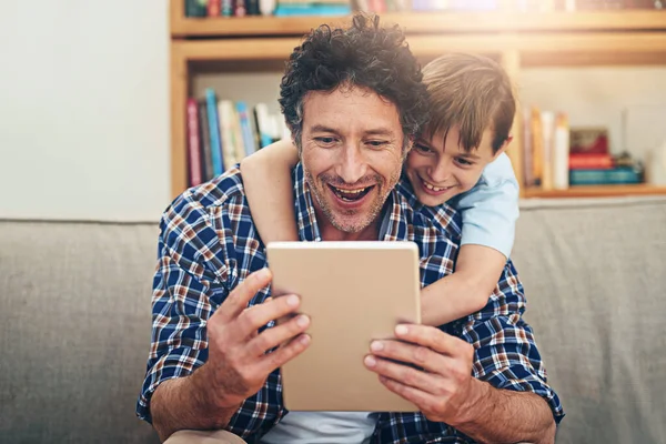 This is a cool app, son. a happy father and his son using a digital tablet together at home