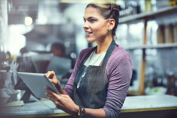 Simplifying small business management with modern technology. a young woman using a digital tablet in the store that she works at