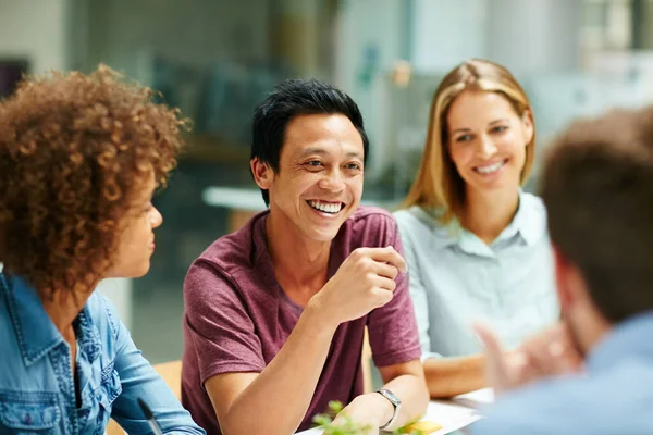 They share a great work relationship. a group of smiling businesspeople talking together around a table in an office
