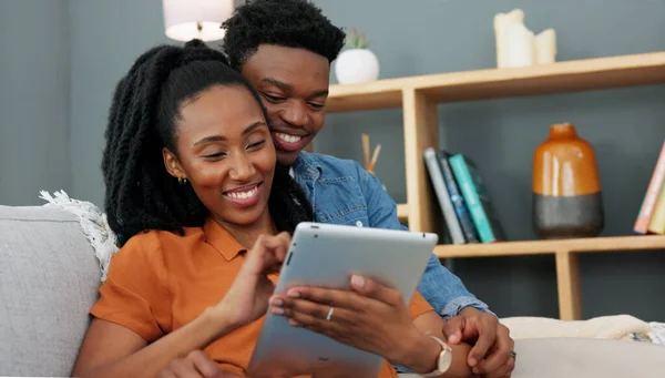 Love, sofa and black couple shopping on tablet while they relax together in the living room. African people compromise, decide and plan home apartment ecommerce order delivery logistics