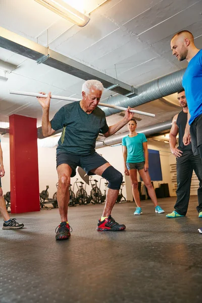 stock image Add this pvc workout into your training. a senior man doing pvc exercises while a group of people watch on