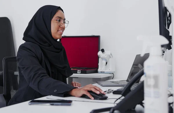 Optometry, consulting and Muslim woman on a computer for research, healthcare and analytics. Ophthalmology, check and doctor reading information, eye results and analysis of medicare on a pc.
