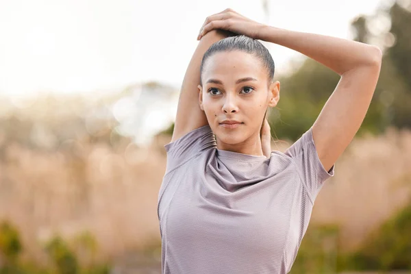 Sports, fitness and woman stretching arms in nature to get ready for workout, training or exercise. Thinking, health or young female athlete stretch and warm up to start exercising, cardio or running.