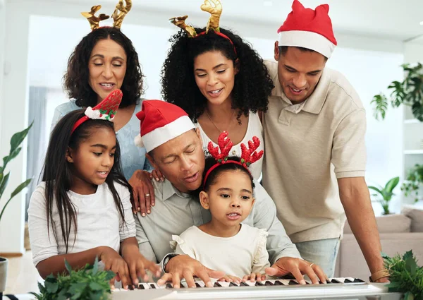 Black family, christmas singing and together at piano for learning, festive celebration or bonding. Father, teaching and girl at keyboard for development, education or holiday for music, mom and kids.
