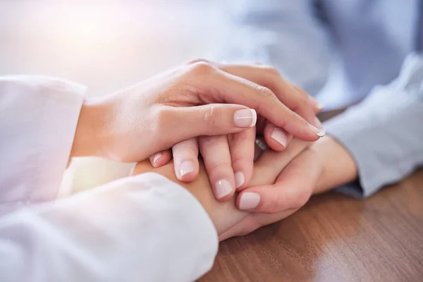 Holding hands, doctor and patient at desk for comfort, talking and communication for bad news, mental health or support. Therapist woman, cancer and together for empathy, care or wellness in hospital.