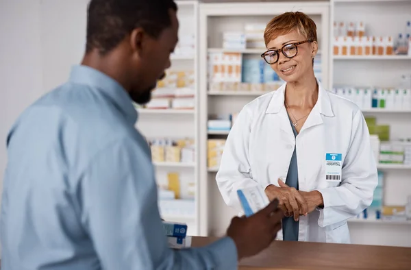 Pharmacist woman, talking to customer about medicine, information or advice on pills box. Black man with pharmacy, clinic or store worker for pharmaceutical, medical and health counter service.