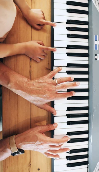 Piano, top view and hands of kid learning with father in home, playing or bonding together. Development, education or parent teaching child how to play music instrument, acoustic or electric keyboard.