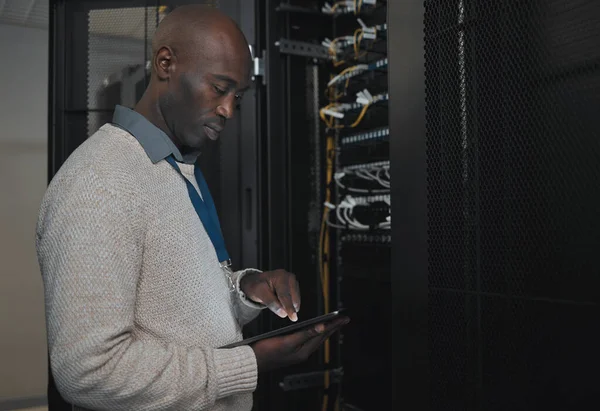 Engineer, server room or black man with tablet for database connection cable, maintenance or software update at night. Cybersecurity, IT and male coder with technology for networking in data center