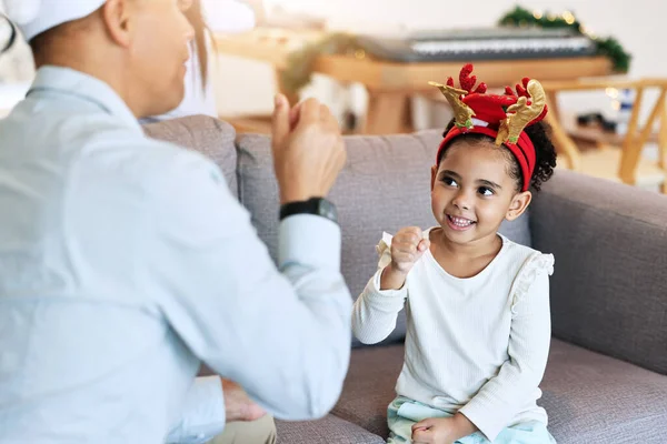 stock image Christmas, girl and home holiday fun with a father and parent care on a living room sofa. Family, vacation bonding and happiness of a child and dad ready for celebration with party hats in a house.