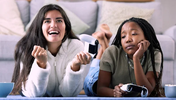 Gaming, winner and women playing a video game and girl celebrating in a home, house or apartment. Friends, console and people with joystick and jealous person due to victory with controller.