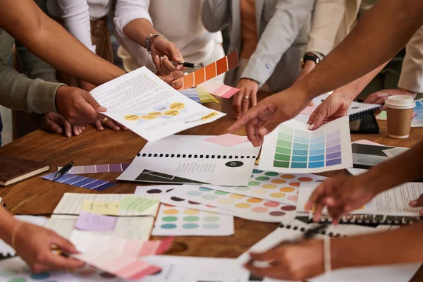 Creative business people, hands and color palette in meeting, planning or brainstorming design strategy at office. Hand of group interior designers in teamwork, project plan or swatches for startup.