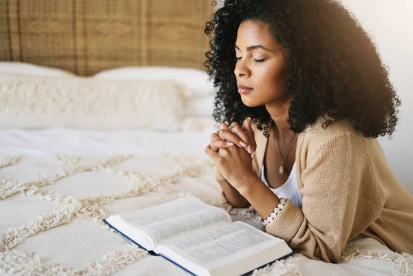 Bible, prayer and black woman praying on bed in bedroom home for hope, help or spiritual faith. God, christian and female worship Jesus or Holy Spirit for forgiveness, compassion or grace in house