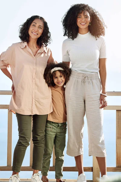 Portrait, black family or children with a senior woman, mother and daughter standing outdoor together on a balcony or veranda. Mothers day, love or kids with a girl, parent and grandparent outside.